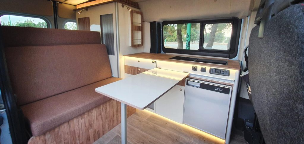 En la foto la mesa plegaba instalada en la camperización de la furgoneta de Sergio, también vemos el interior y el asiento cama