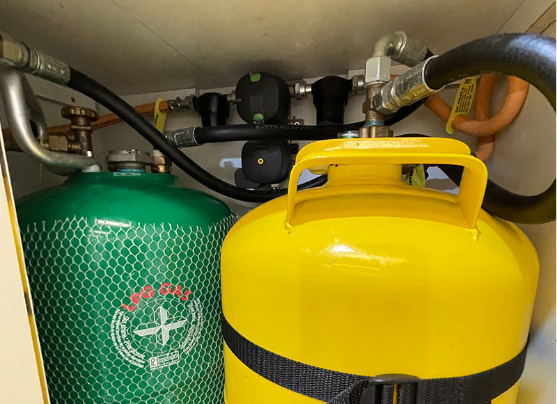 Foto de una instalación de gas en el mueble de la furgoneta, con sus latiguillos y sus válvulas de presión
